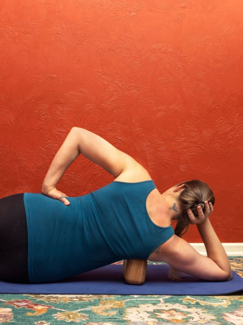 Maria demonstrating a side-lying Block Therapy release with the block positioned along the hip and low back